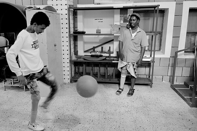 Abdullah und ein anderer Mann spielen Fußball in einem Raum